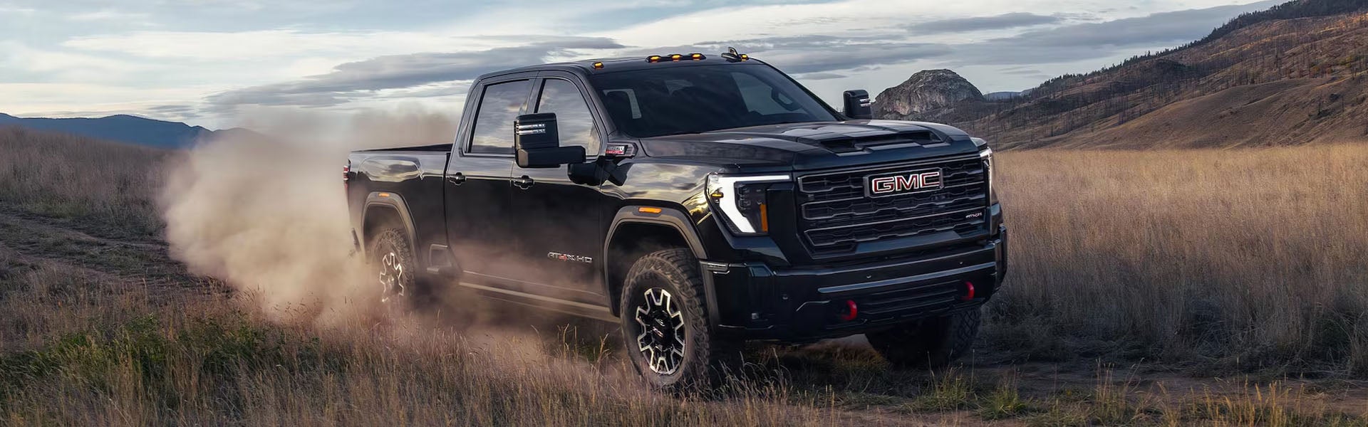 A black GMC Sierra 2500 driving trhough a dusty field